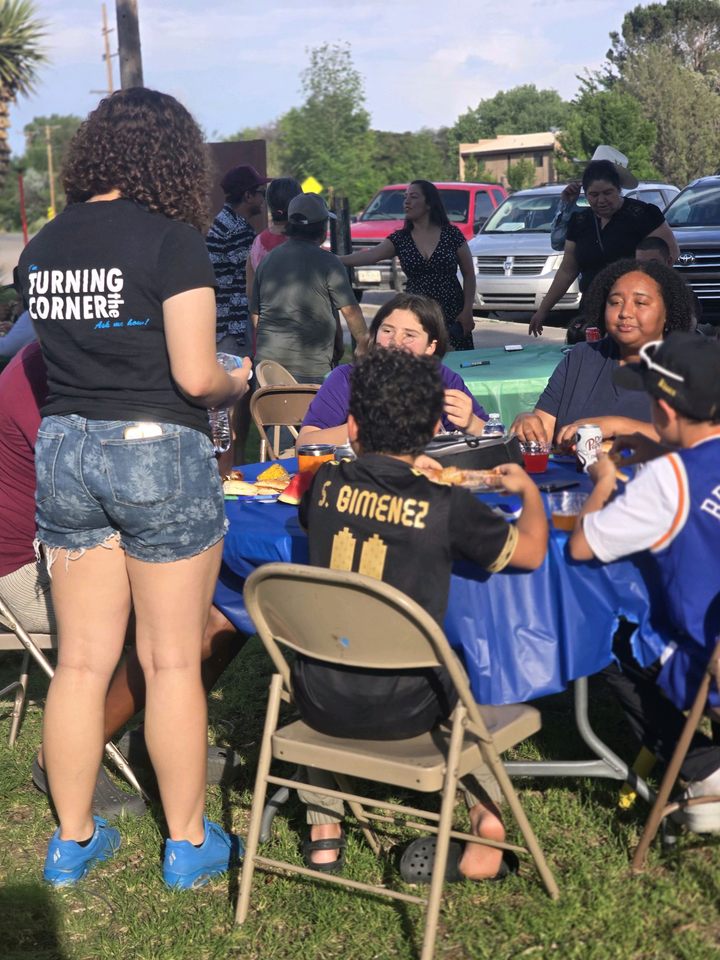 Neighbors at an outdoor table, one in a Turning Corners shirt