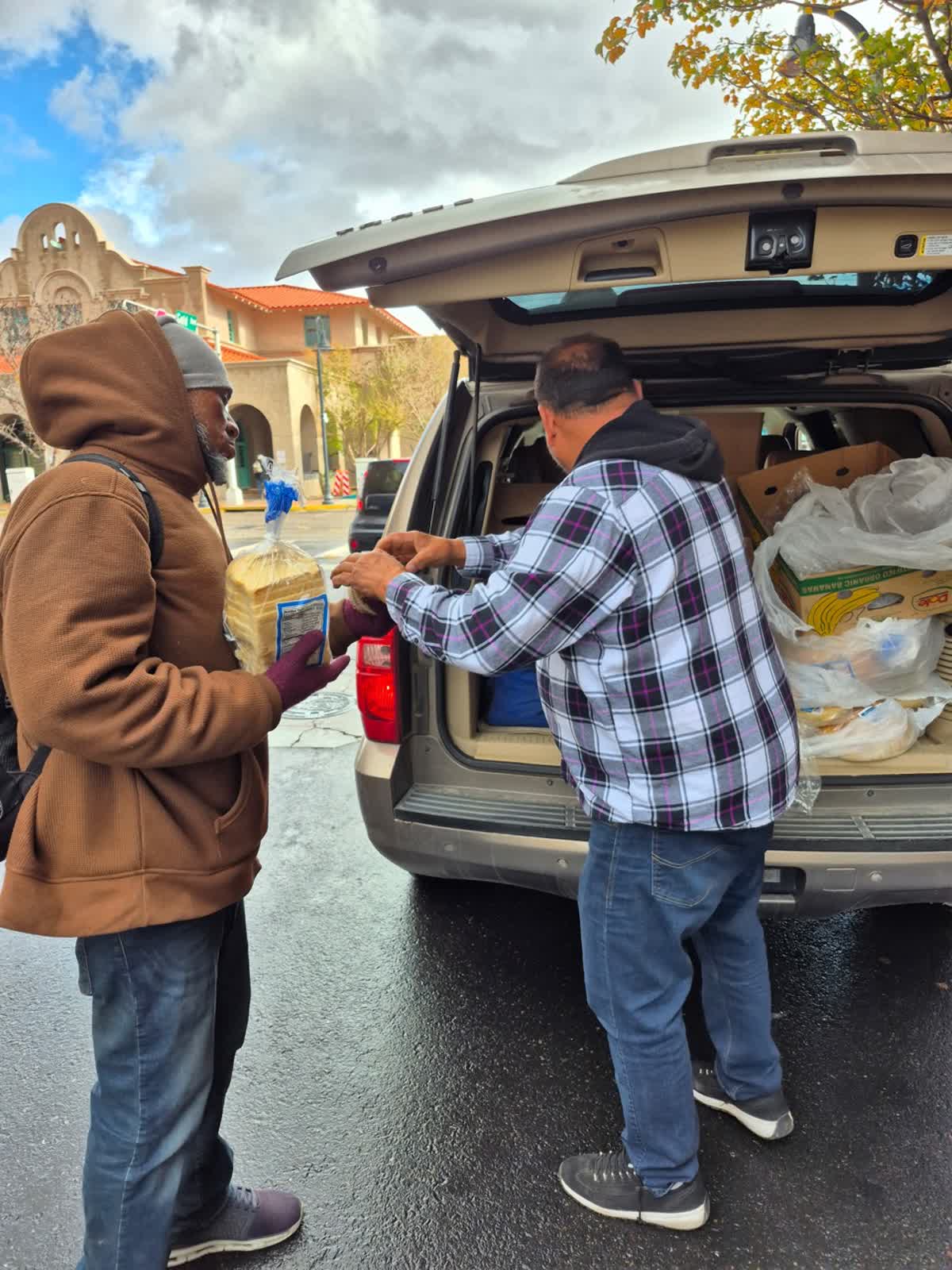 A volunteer handing out food on a downtown street