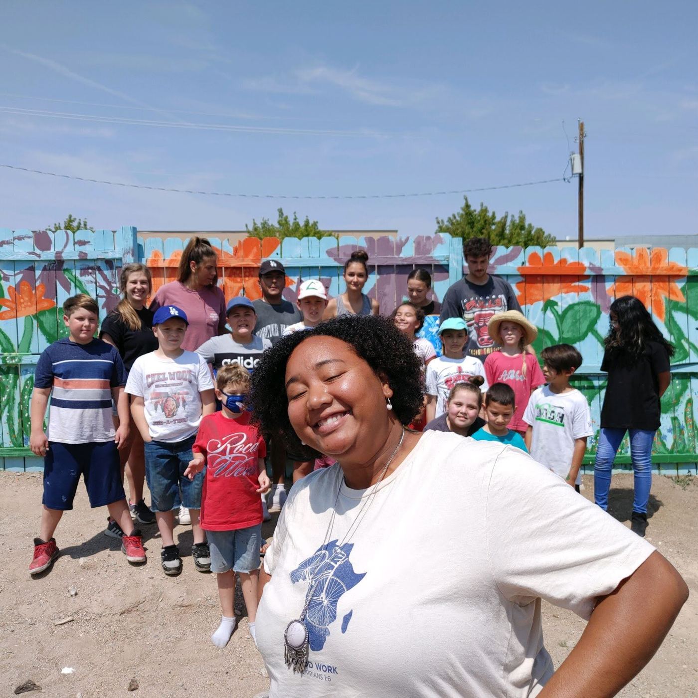 Children and a teacher in front of a mural on the Kingdom Builders playground