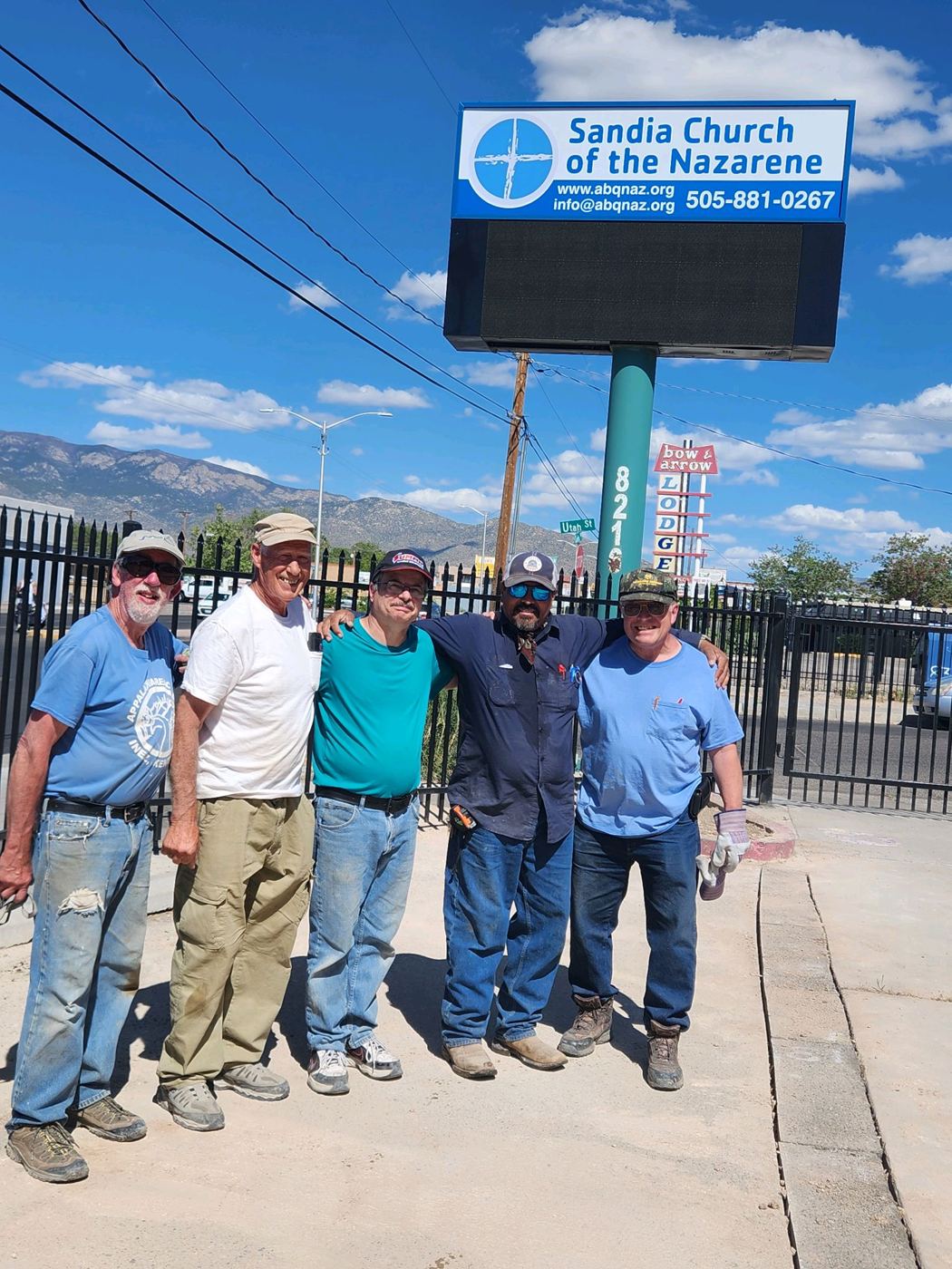 A work crew in front of the Sandia Church sign